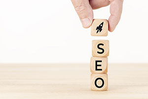 Optimisation pour les moteurs de recherche - Main humaine empilant des blocs SEO